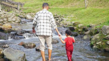 Baba ve kızı nehirde el ele oynuyorlar.