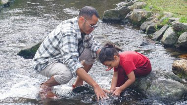 Baba ve kızı nehirde el ele oynuyorlar.