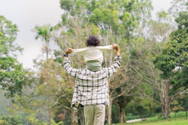 Baba ve kızının park bahçesinde sırt sırta koşarkenki görüntüsü.