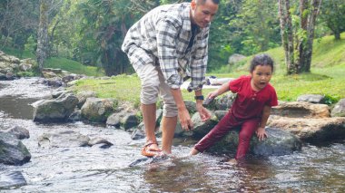 Baba ve kızı nehirde el ele oynuyorlar.
