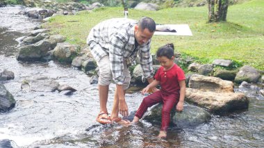 Baba ve kızı nehirde el ele oynuyorlar.