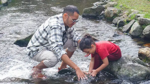 Baba ve kızı nehirde el ele oynuyorlar.