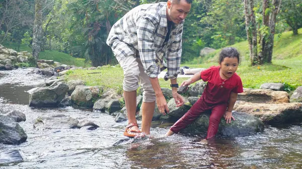 Baba ve kızı nehirde el ele oynuyorlar.
