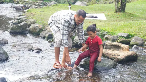 Baba ve kızı nehirde el ele oynuyorlar.