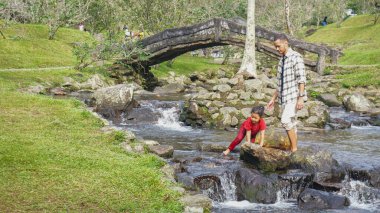 Baba ve kızı nehirde el ele oynuyorlar.