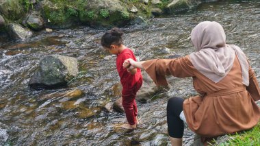 Başörtüsü Anne ve kızı nehirde birlikte oynuyorlar ve el ele tutuşuyorlar.