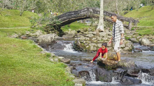 Baba ve kızı nehirde el ele oynuyorlar.