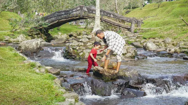 Baba ve kızı nehirde el ele oynuyorlar.