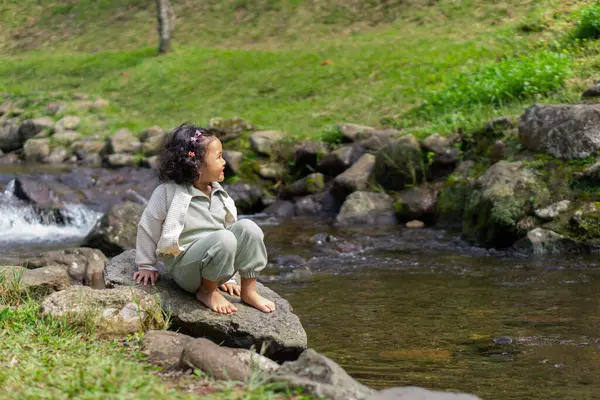 Kıvırcık saçlı bir kız, gülen yüzlü bir nehirde tatil yapar.