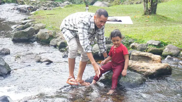 Baba ve kızı nehirde el ele oynuyorlar.