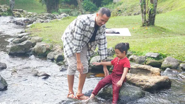 Baba ve kızı nehirde el ele oynuyorlar.