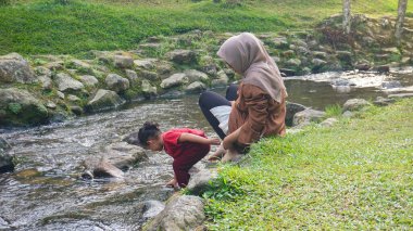 Başörtüsü Anne ve kızı nehirde birlikte oynuyorlar ve el ele tutuşuyorlar.