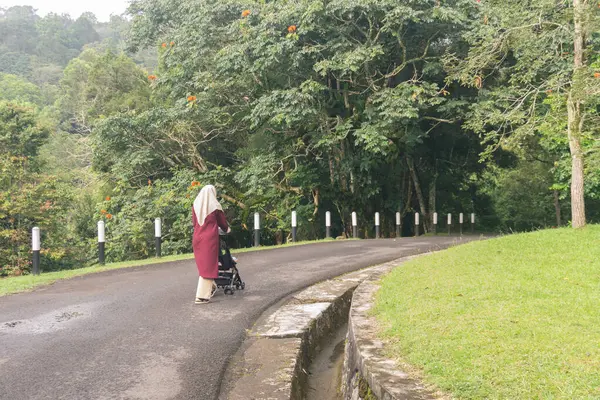 Jilbab annesi çocuğuyla parkta tek başına yürüyor.