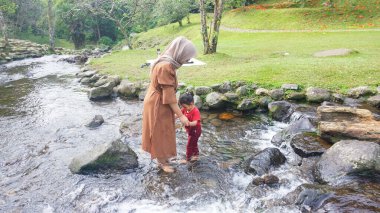 Başörtüsü Anne ve kızı nehirde birlikte oynuyorlar ve el ele tutuşuyorlar.