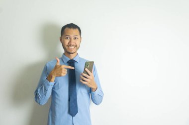 Kravatlı bir iş adamı akıllı telefonu parmağıyla işaret ediyor ve gülümsüyor.