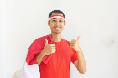 Genç Endonezyalı adam baş parmağına saç bandı taktı ve Endonezya bayrağı beyazları izole etti