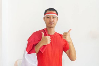 Genç Endonezyalı adam baş parmağına saç bandı taktı ve Endonezya bayrağı beyazları izole etti