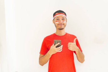 Genç Endonezyalı adam, izole edilmiş beyaz saç bandıyla cep telefonuna parmak bastı