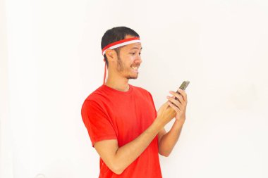 Endonezyalı genç adam, izole edilmiş beyaz saç bandıyla cep telefonu tutarken heyecanlandı.