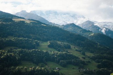 Majestic mountains in the Alps covered with trees and clouds