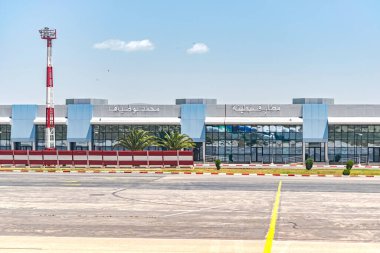 Constantine, Cezayir 25 Mart 2025: Modern terminal binalı Mohamed Boudiaf Havaalanı 'na varış pisti. Arapça bir işaret güneşli mavi gökyüzünün altında havalimanı adını gösterir. 