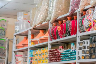 Bechar, Cezayir - 29 Aralık 2022: Berber stili vazolarla sergi rafları, Hint kostümleri, baharatlar, otlar, zencefilli kutular ve plastik kutularla dolu büyük şeffaf çantalar