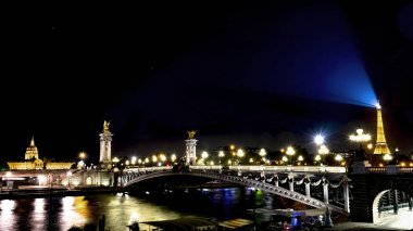 Paris, Fransa - 19 Ekim 2018 Seine nehri üzerindeki 3. Alexander Köprüsü, altın renkli Hotel des Invalids ve Eyfel Kulesi sokak lambaları suya yansıyor ve geceleri karanlık gökyüzünü aydınlatıyor..