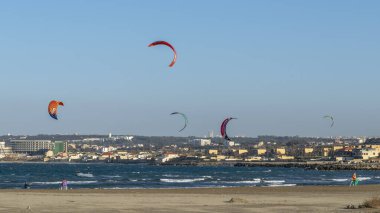 Cezayir, Cezayir... 25 Ocak 2022, uçurtma okulu, uçurtma. Marina Sidi Fredj yelkencilik kulübü, Staoueli. Plaj sörfçüleri. Deniz dalgaları. Derin mavi deniz, kum. Moretti şehri. Holyday Oteli Kulesi.