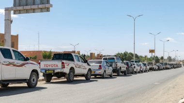 Tamanrasset, Cezayir - Aril 13, 2025: Çöldeki Naftal benzin istasyonu yakınlarındaki yakıt sıkıntısı nedeniyle uzun bir süre yol kenarına park etmiş kamyonlar..