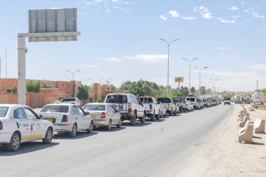 Tamanrasset, Cezayir - Aril 13, 2025: Naftal benzin istasyonunda yaşanan akaryakıt sıkıntısı nedeniyle uzun bir süre yol kenarında park halindeki kamyonlar ve tank kamyonları kuyruğu.