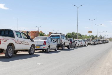 Tamanrasset, Cezayir - Aril 13, 2025: Çöldeki Naftal benzin istasyonu yakınlarındaki yakıt sıkıntısı nedeniyle uzun bir süre yol kenarına park etmiş kamyonlar..