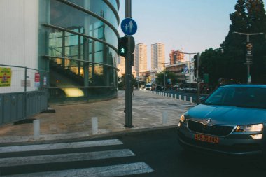 Araba caddeye geri dönüyor. İsrail 'in Tel Aviv kentindeki günbatımı binaları