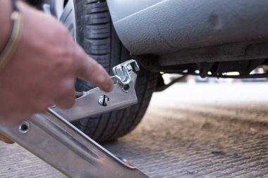 using a car jack to change a flat tire and put spare tire