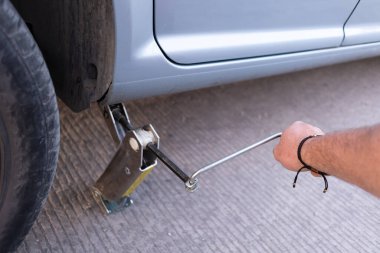 point of view of a young man using a car jack