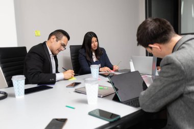 Bir toplantı odasında beyin fırtınası fikirleri yazan iş adamları ve iş kadınlarından oluşan karışık bir grup.