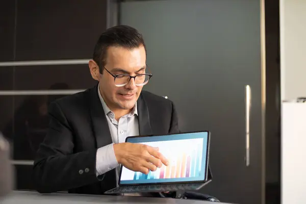 Genç patron iş adamı, bir konferansta tabletinin grafiklerini gösteriyor ve işaret ediyor.