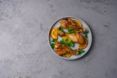 Bal sosunda pişirilmiş tavuk budu ve portakallar tabakta..