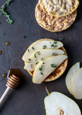 Koyu beton bir masada ballı mısır ekmeği ve dilimlenmiş armut. Yukarıdan görüntüle.