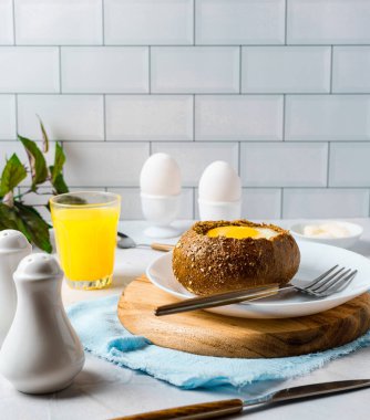 Çörekte pişmiş yumurta. Basit ürünlerden yapılan lezzetli bir kahvaltı. Peynir, sosis, domates, yumurta ve çıtır ekmek! Mutfakta hızlı bir kahvaltı..