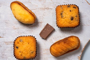 Muffinler ve çikolatalı bisküviler tahtada. Kapat, üst görünüm.