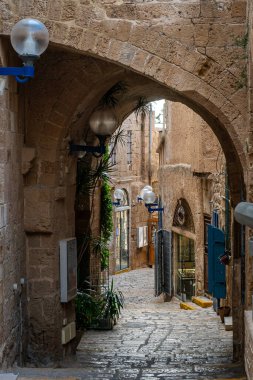 Eski Jaffa 'da, taş kemerlerin altında saklı bir sokak, yüzyılların sırlarını barındırıyor gibi görünüyor. Oyma taş duvarlar mahremiyet ve eski bir cazibe ortamı yaratır..