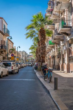 İsrail, Tel Aviv - 29 Aralık 2024: Eski Jaffa 'da bir sokak: Yol boyunca palmiye ağaçları ve balkonları olan zarif bir bina, antik şehrin atmosferini ve benzersiz cazibesini yansıtıyor..