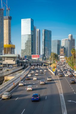 İsrail, Tel Aviv - 19 Ocak 2025: Modern gökdelenleri, işlek bir otoyolu ve bir kanalı olan Tel Aviv şehri. Parlak gökyüzü ve şehir atmosferi metropolün dinamik bir resmini oluşturuyor..
