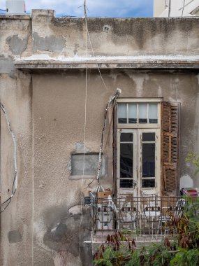 Ahşap pencereli ve açık panjurlu eski bir soyma duvarı. Etrafı yeşilliklerle çevrili metal parmaklıklar ve sandalyelerle dolu küçük bir balkon. Eski şehrin şehir cazibesi..