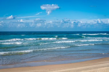 İsrail, Tel Aviv 'in kumsalında Akdeniz' in turkuaz dalgaları bulutlu mavi gökyüzünün altında. Resimli deniz manzarası bir rahatlama, özgürlük ve sükunet atmosferi taşıyor..