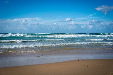 İsrail, Tel Aviv 'in kumsalında Akdeniz' in turkuaz dalgaları ve bulutlarla süslenmiş mavi gökyüzü. Resmedilmeye değer doğal manzara, barış ve tazelik dolu bir atmosfer..