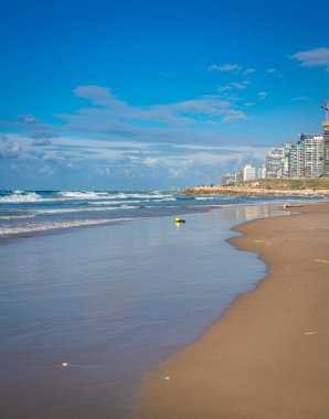 İsrail, Tel Aviv - 29 Aralık 2024: Akdeniz 'in turkuaz dalgaları ve modern yüksek binalarla kumsal. Şehir deniz manzarası doğanın uyumunu yansıtıyor..