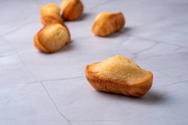 Beyaz mermer arka planda Fransız kurabiyelerinin yakın çekimi. Altın sünger desenli ve hafif ışıklı minimalist fırın kompozisyonu. Basit bir tatlı..