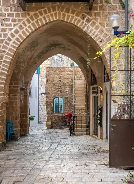 İsrail, Jaffa - 17 Aralık 2024. Jaffa şehrinde kemerli taş binalar, tarihi mimari, merdivenli bir ara sokak, bitkiler ve park edilmiş bir bisiklet..