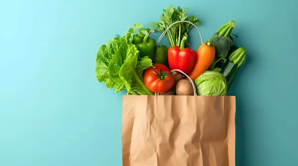Canlı mavi bir arka planda kağıt torbada taze sebze ve sosisler..
